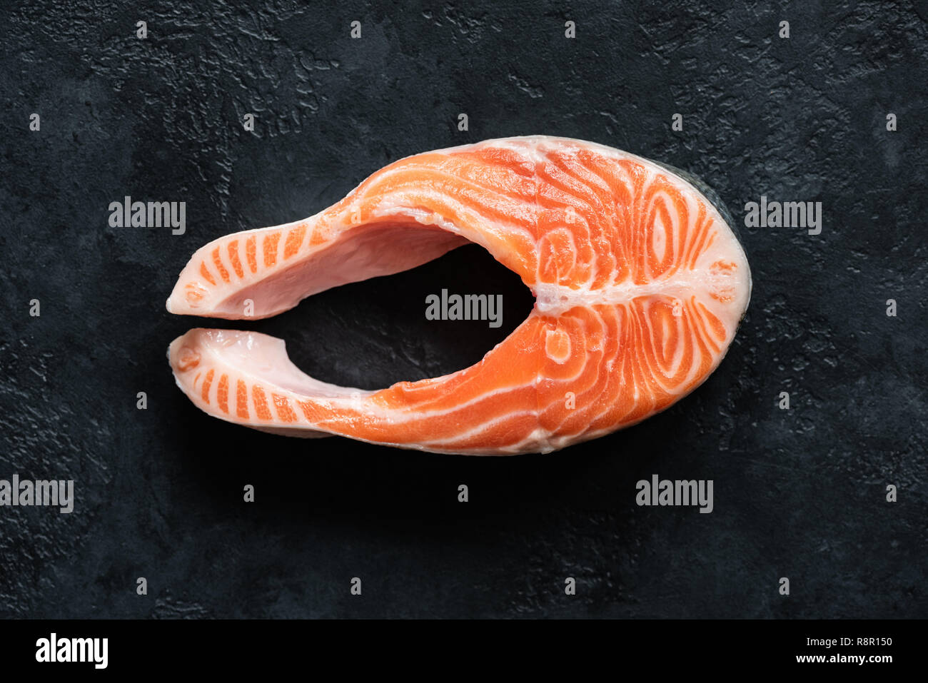 Frische rohe Lachssteak auf Schwarz konkreten Hintergrund, Ansicht von oben. Nicht gegartem Fisch Steak Stockfoto