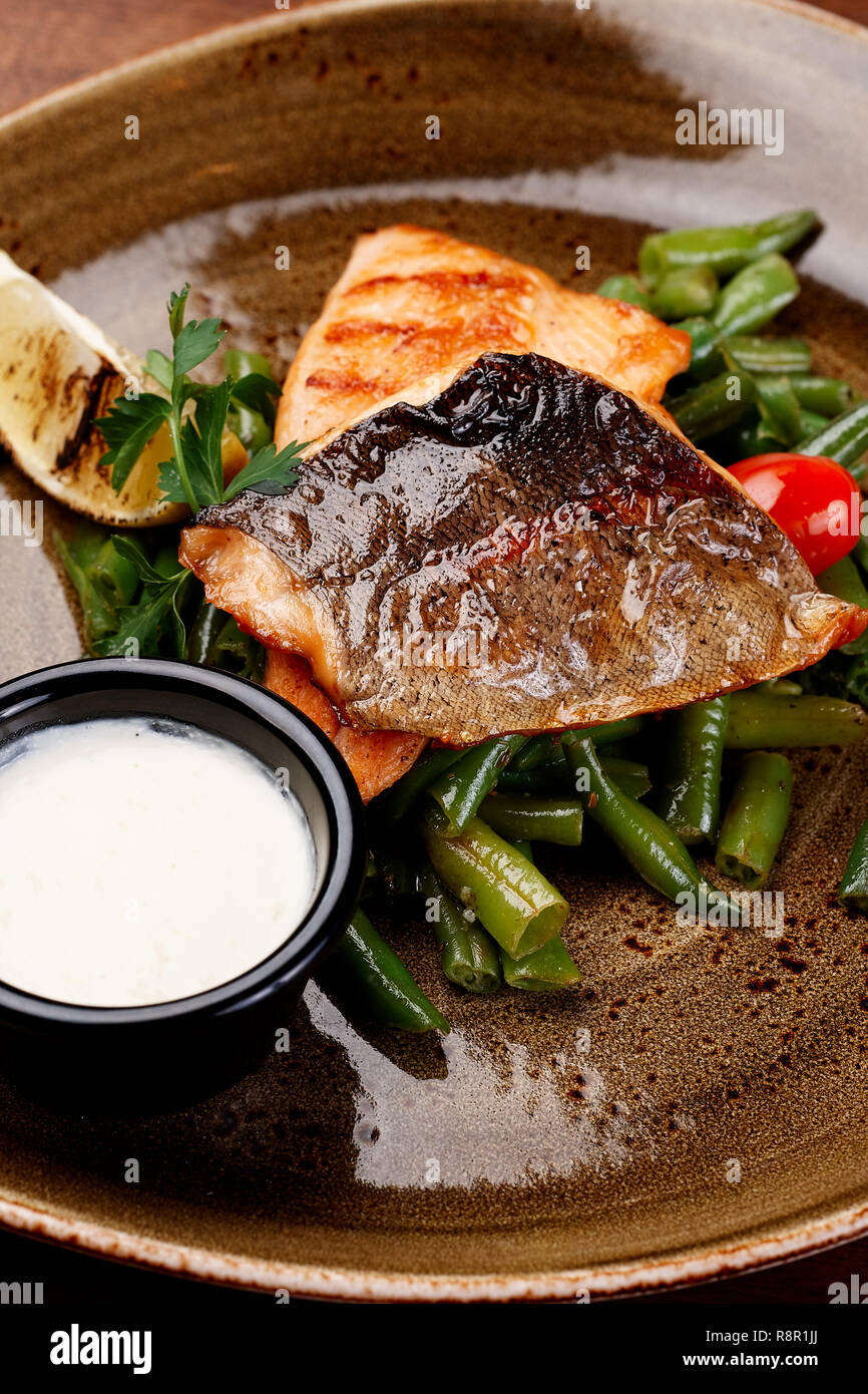Grill Lachsfilet auf Platte mit Spargel Sauce. Frisch gebratene Fisch Steak Teller, Gemüse Tomaten serviert im Restaurant. Gesundes Mittagessen Konzept Seite V Stockfoto