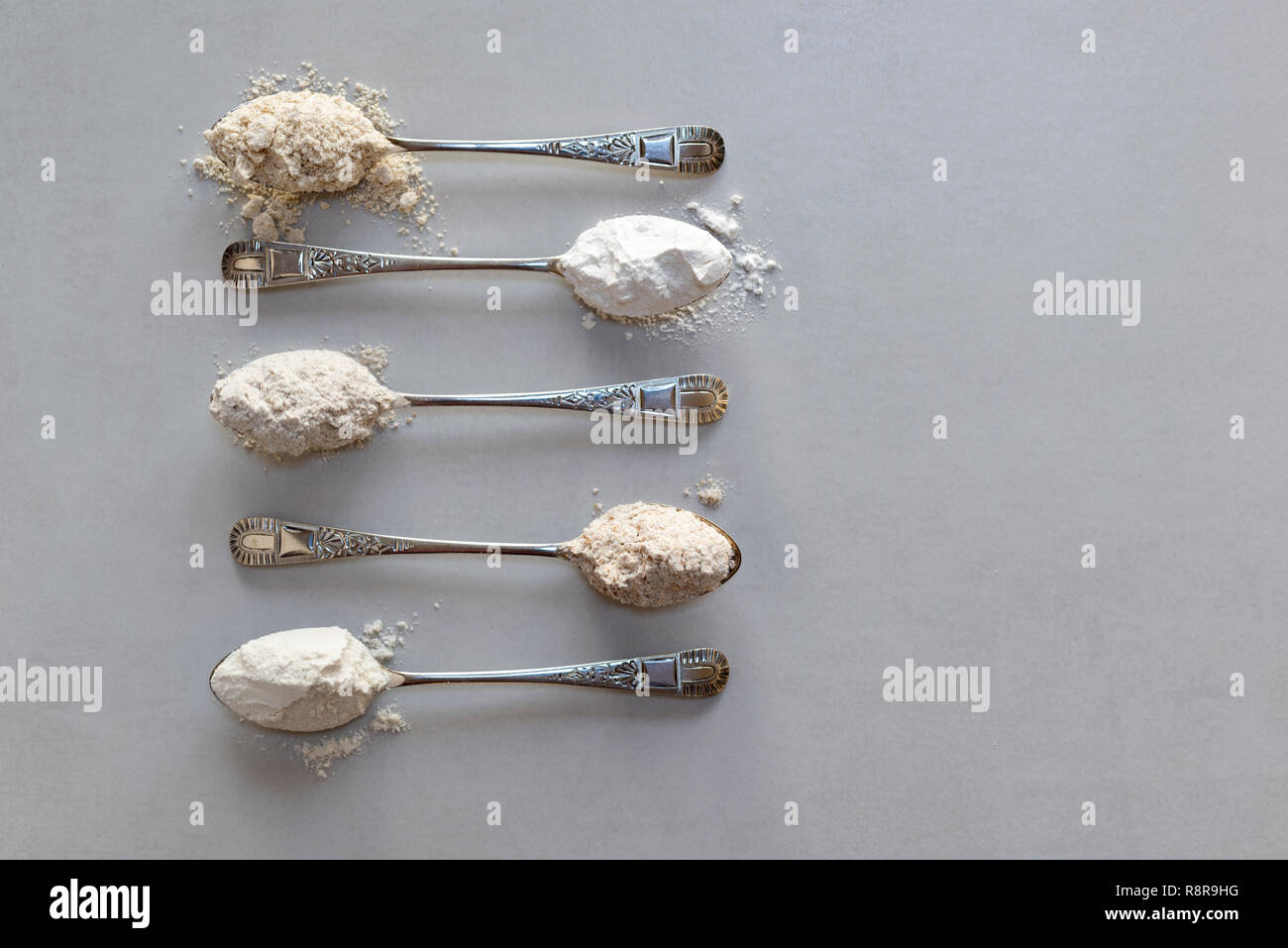 Fünf Esslöffel verschiedene Mehle. Von oben: Hafer, Reismehl, Roggenmehl, vollkornmehls, glattes Mehl. Stockfoto