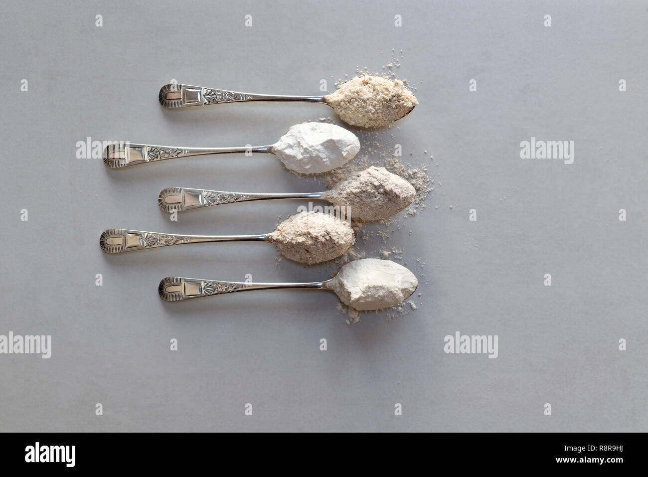 Fünf Esslöffel verschiedene Mehle. Von oben: Hafer, Reismehl, Roggenmehl, vollkornmehls, glattes Mehl. Stockfoto