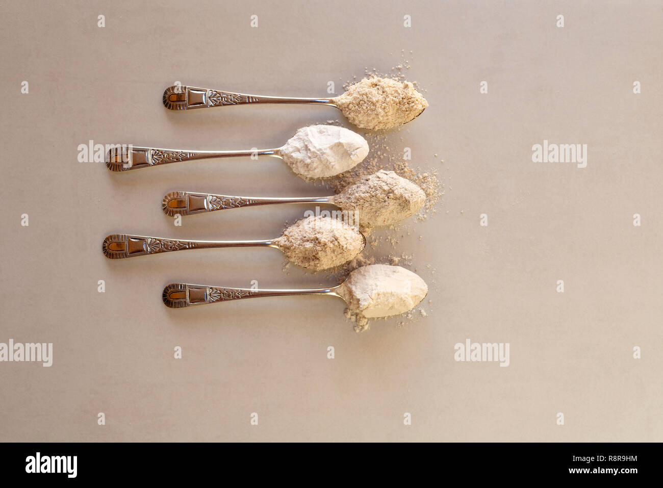 Fünf Esslöffel verschiedene Mehle. Von oben: Hafer, Reismehl, Roggenmehl, vollkornmehls, glattes Mehl. Stockfoto