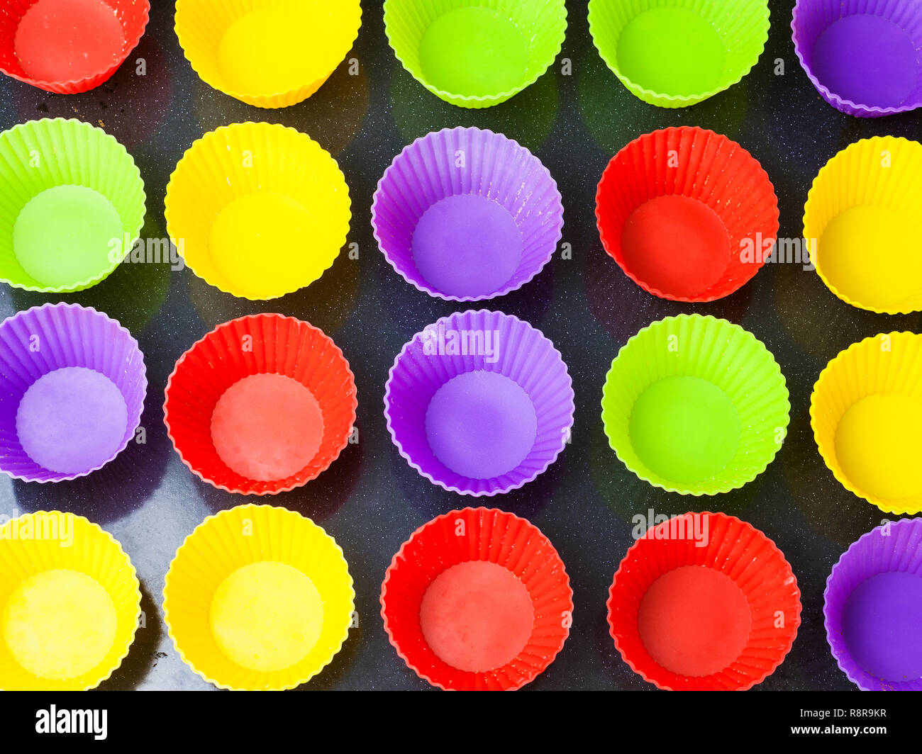 Blick von oben auf die vielen leeren bunte Silikonformen für die Muffins im Backblech Stockfoto