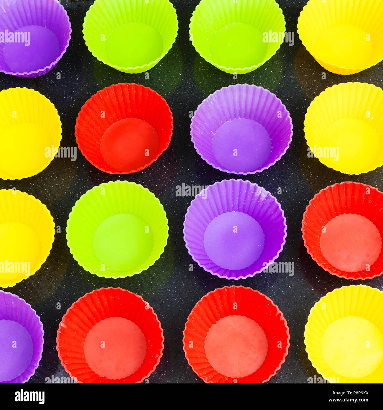 Blick von oben auf die vielen leeren multicolor Silikonformen für Cupcakes auf Backblech Stockfoto