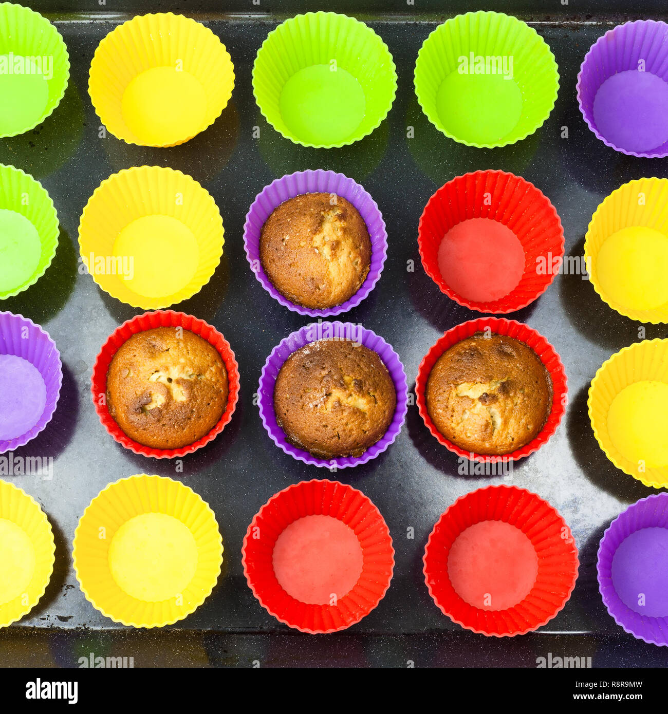 Blick von oben auf die paar gebackene Muffins und viele leere multicolor Silikonformen auf dunklen Fach Stockfoto
