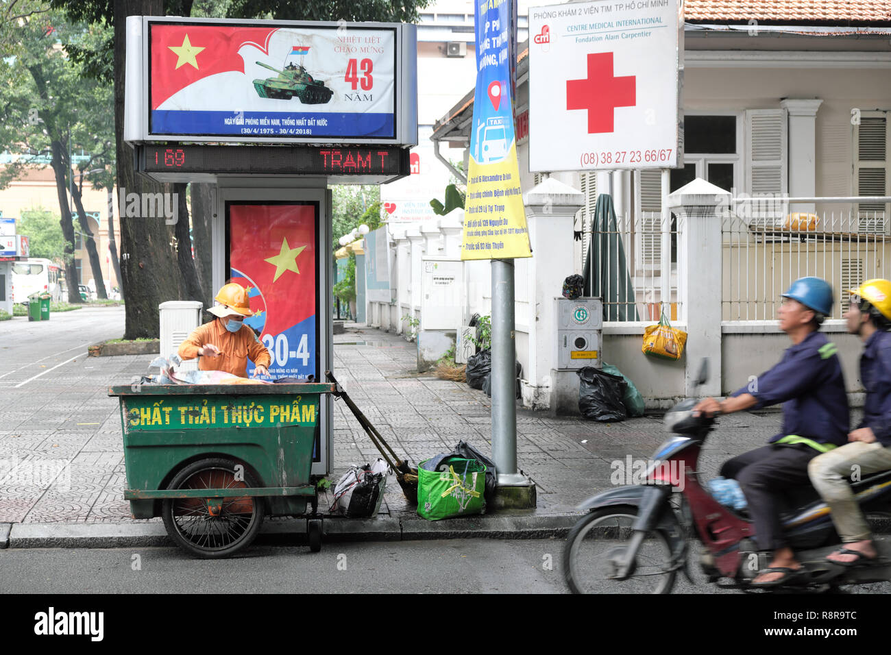 Ho Chi Minh City, Vietnam - Street Sweeper Reinigung Straßen in der Nähe der Kommunistischen Partei Plakate feiert 43 Jahre seit die Stadt wurde 1975 befreit Stockfoto