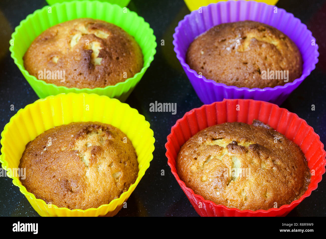 Frisch gebackene Muffins in bunten Silikonformen schließen bis auf dunklen Fach Stockfoto