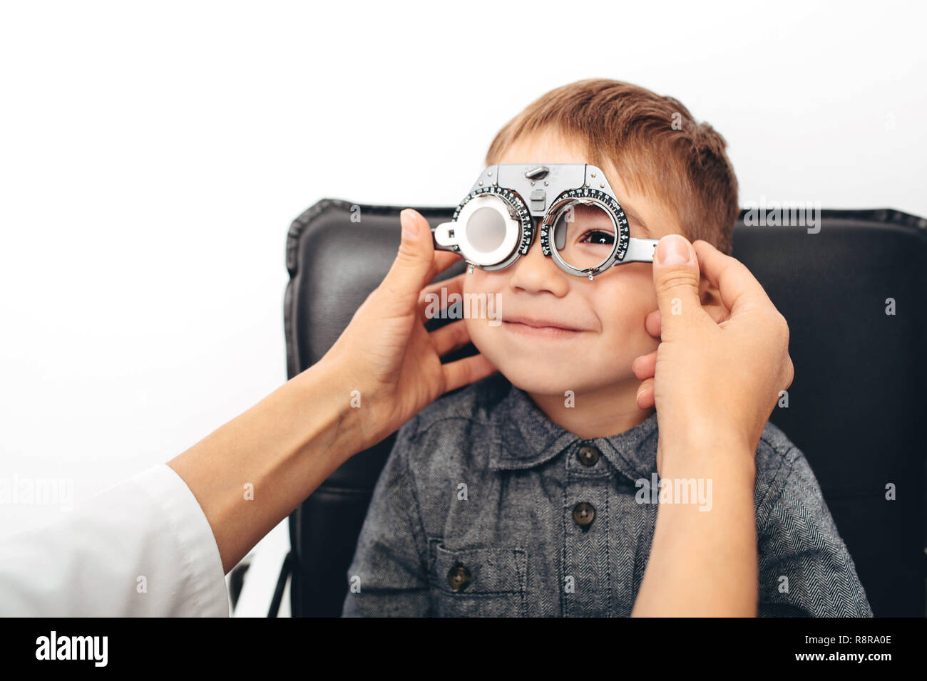 Optiker prüfen Vision von einem wenig freundlichen jungen mit Trial Rahmen Stockfoto