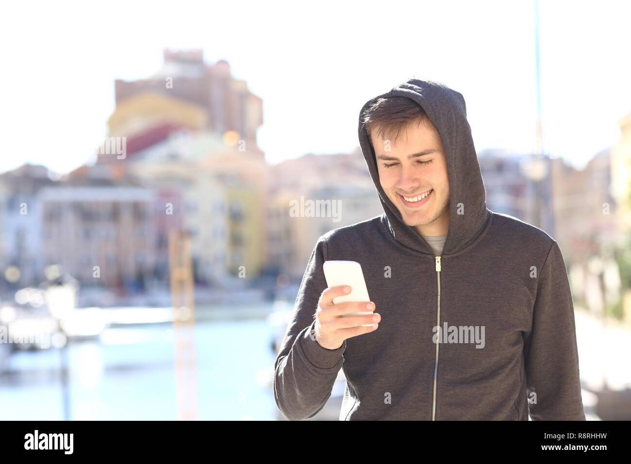 Happy Teenager Kontrolle smart phone zu Fuß in einer Küstenstadt Stockfoto