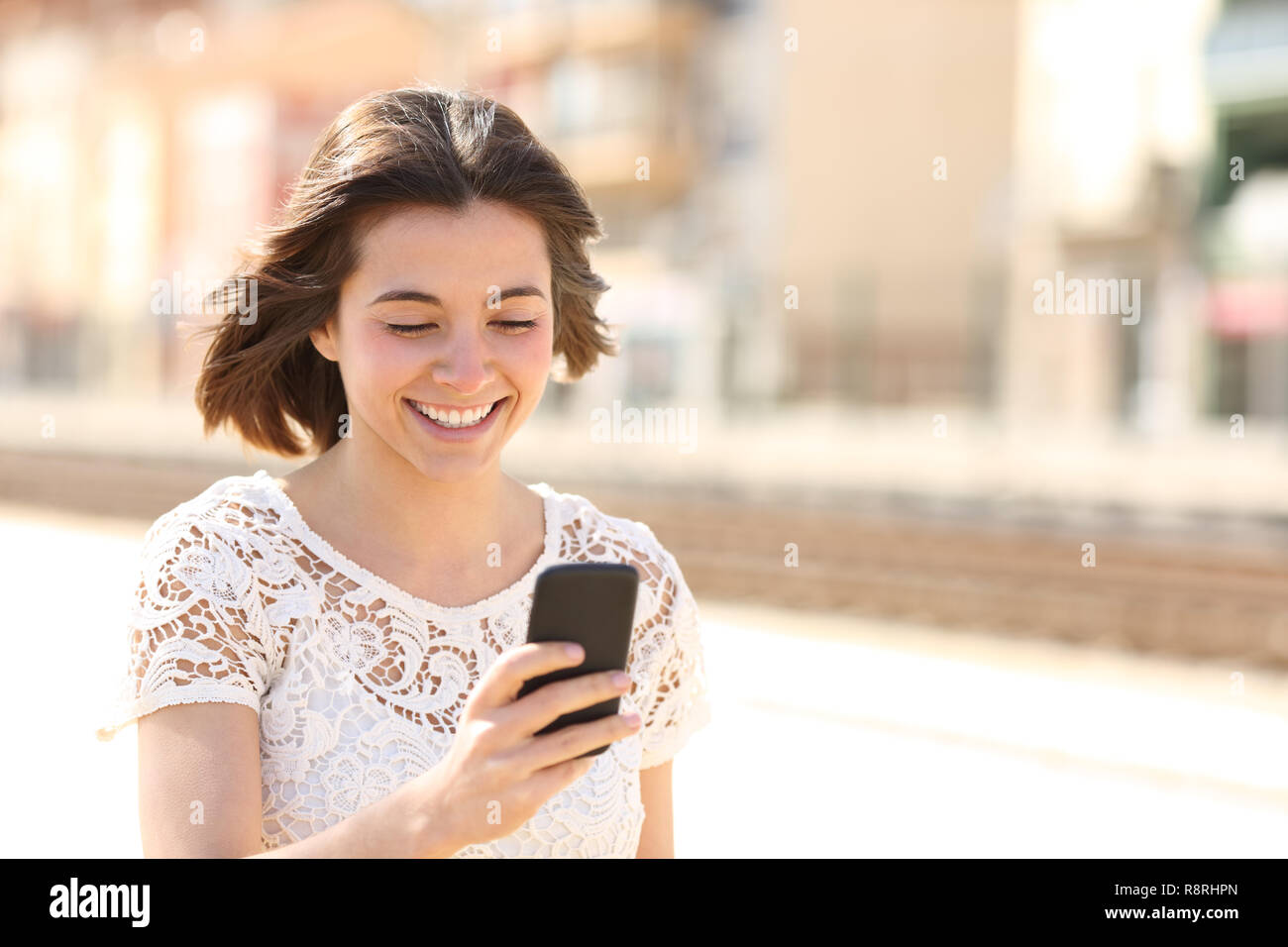 Glückliche Frau Fuß Kontrolle smart phone Inhalt auf der Straße Stockfoto
