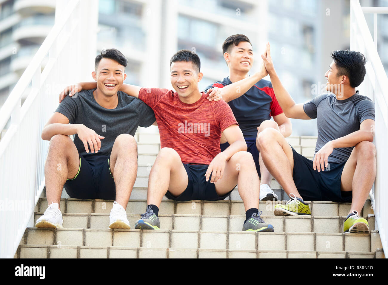 Gruppe von vier glückliche junge asiatische männliche Athleten sitzen auf Schritte entspannend Stockfoto