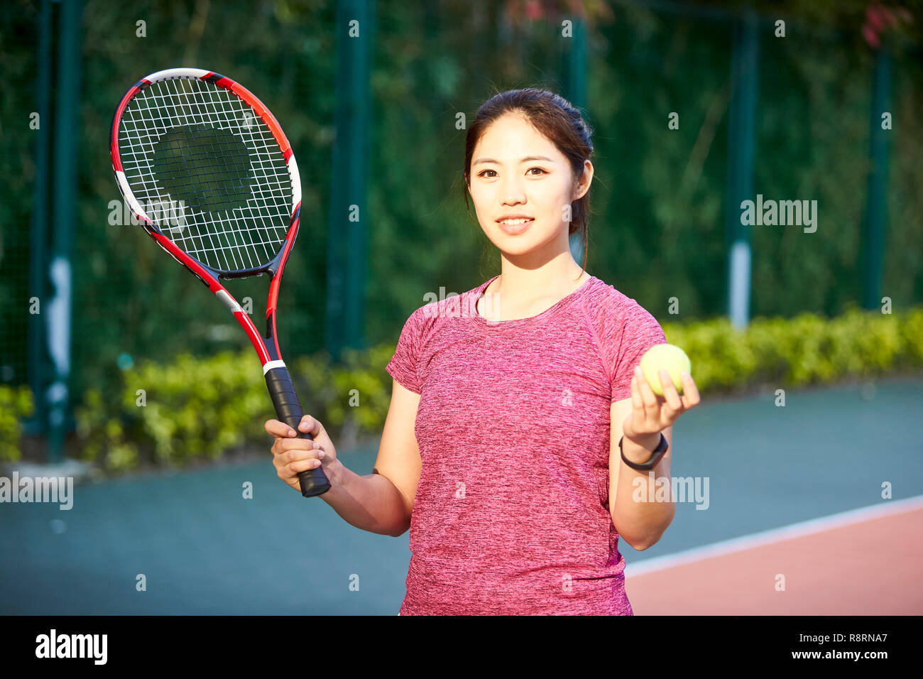 Outdoor portrait einer jungen asiatischen Tennisspieler an der Kamera schaut lächelnd Stockfoto