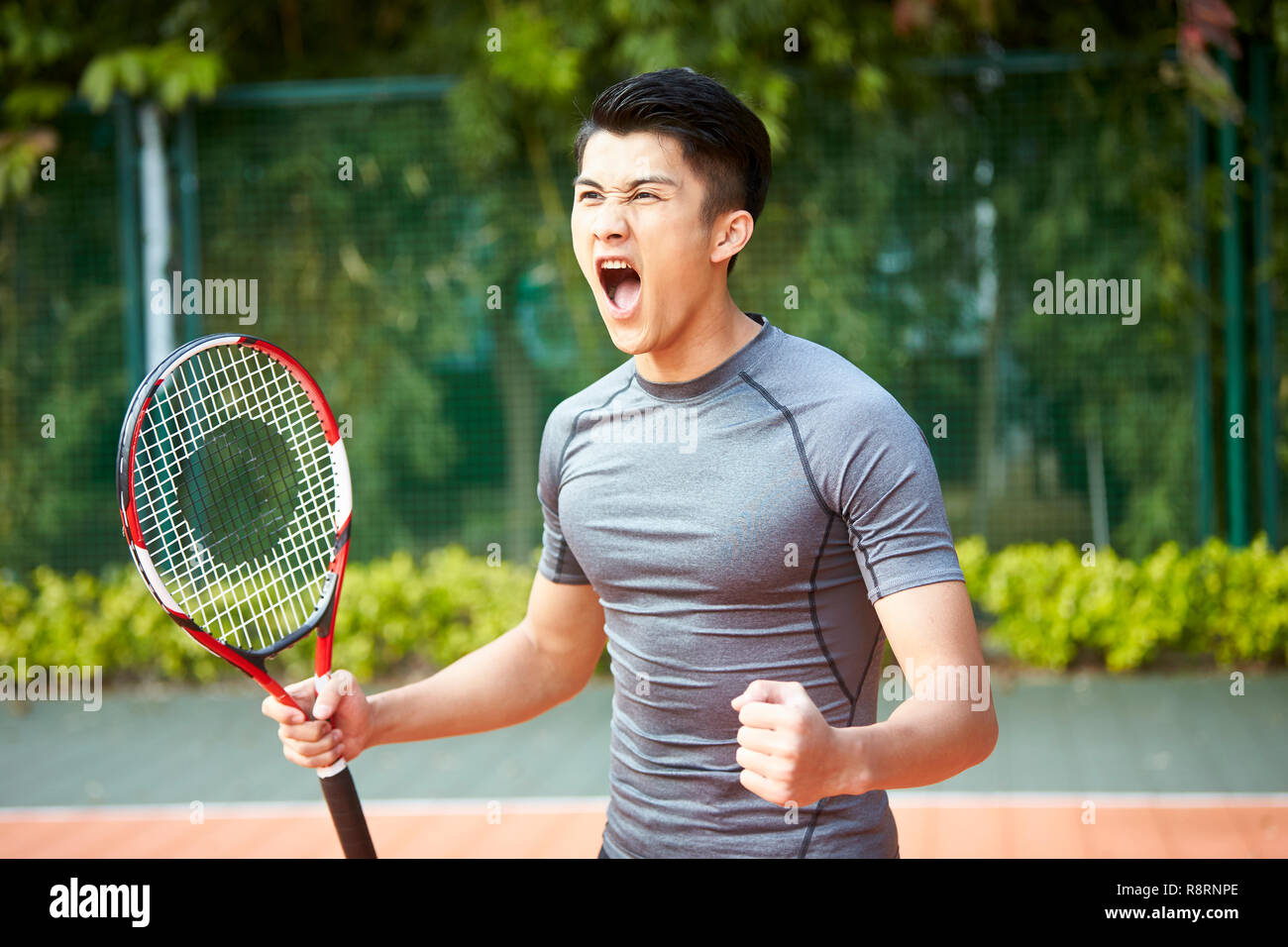 Jungen asiatischen männlichen Tennisspieler feiern nach einen Punkt Stockfoto