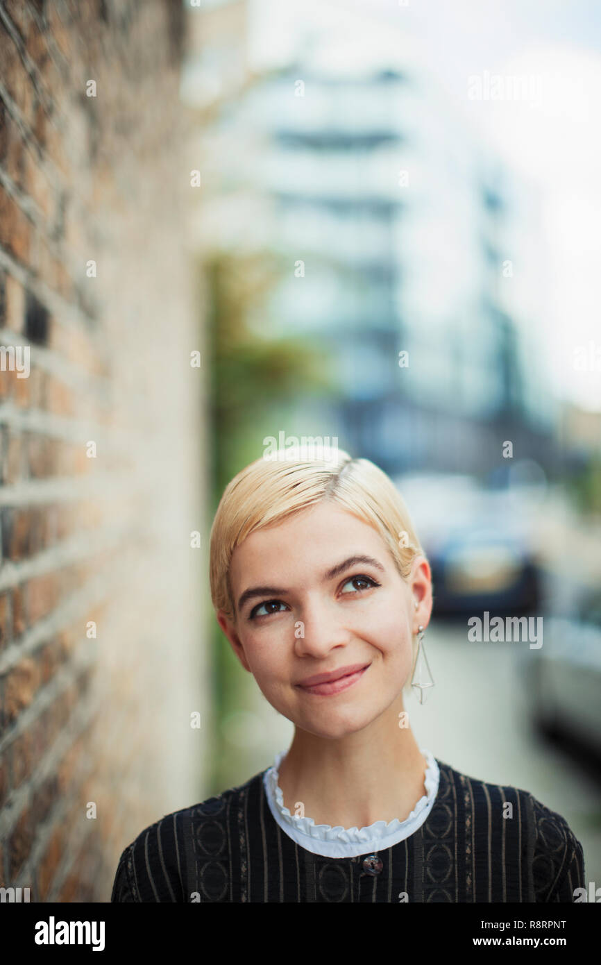 Portrait zuversichtlich, neugierige junge Frau auf städtischen Bürgersteig Stockfoto