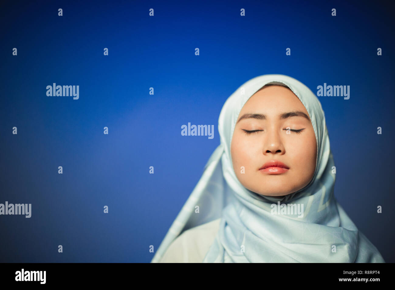 Ruhige junge Frau trägt blaue Seide hijab Stockfoto