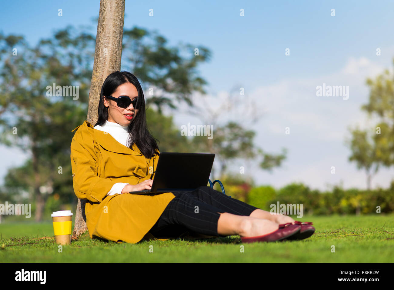 Mädchen Arbeiten am Laptop im Park außerhalb des Büros Stockfoto