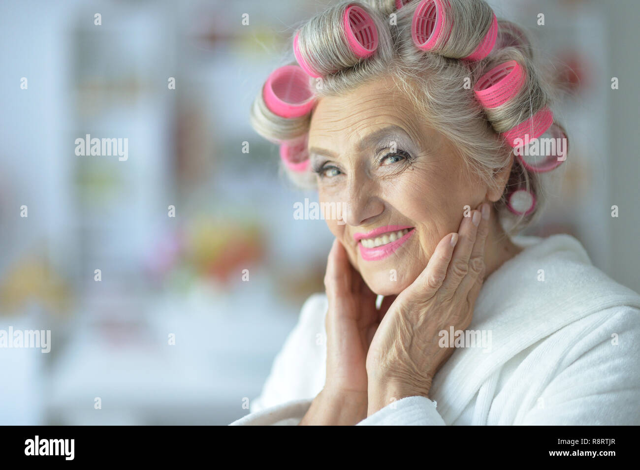Portrait der älteren Frau im Bademantel und mit Lockenwicklern Stockfoto