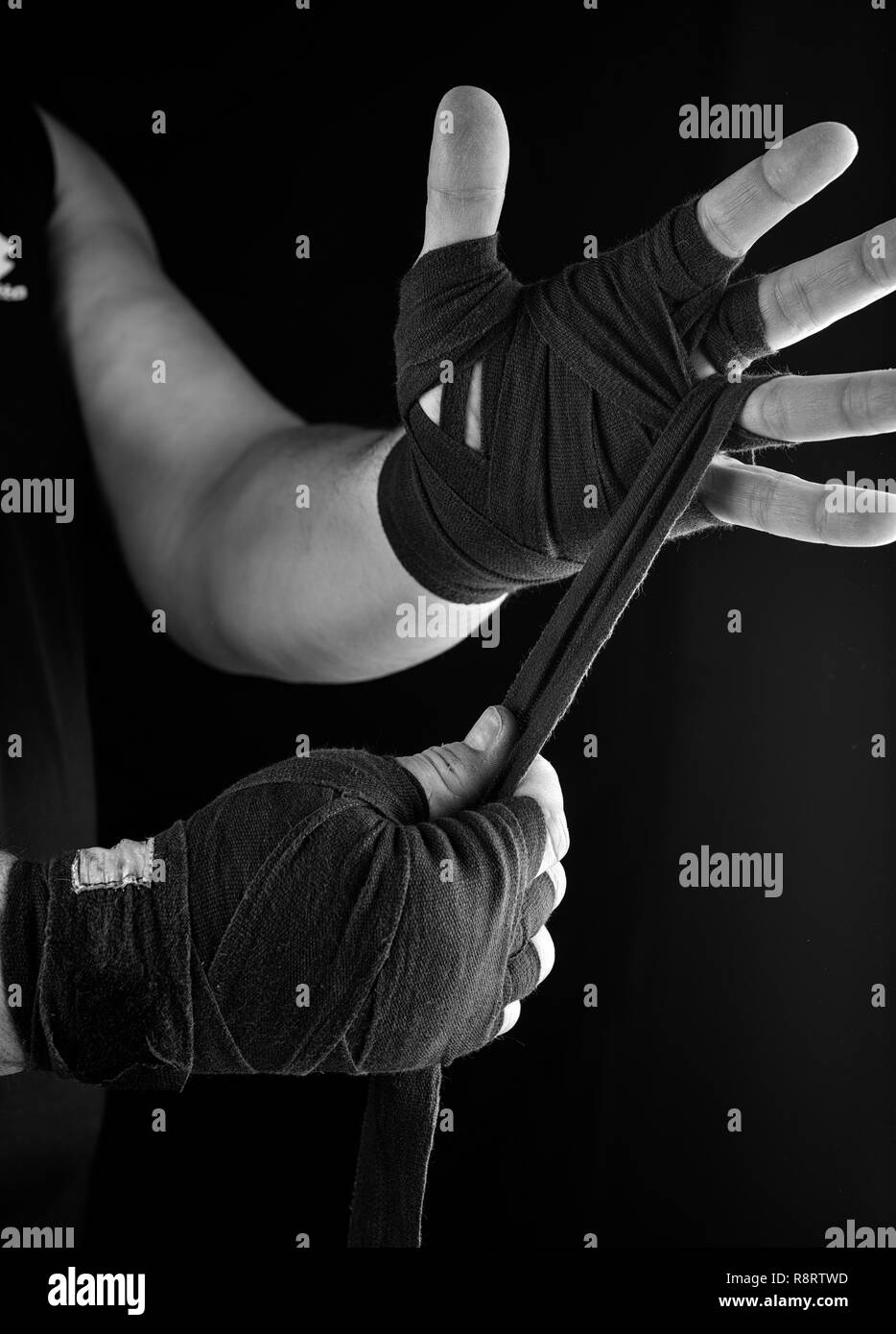 Man wickelt seine Hände in Schwarz textile Bandage für Sport, schwarz weiss Toning Stockfoto