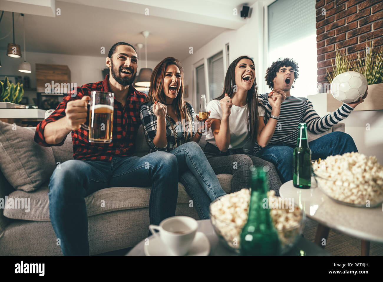 Freunde sind Fans von Sport Spiele wie Fußball lieben ihre Freizeit zu Hause zusammen. Sie sind Schreiend und gestikulierend für einen Sieg. Stockfoto