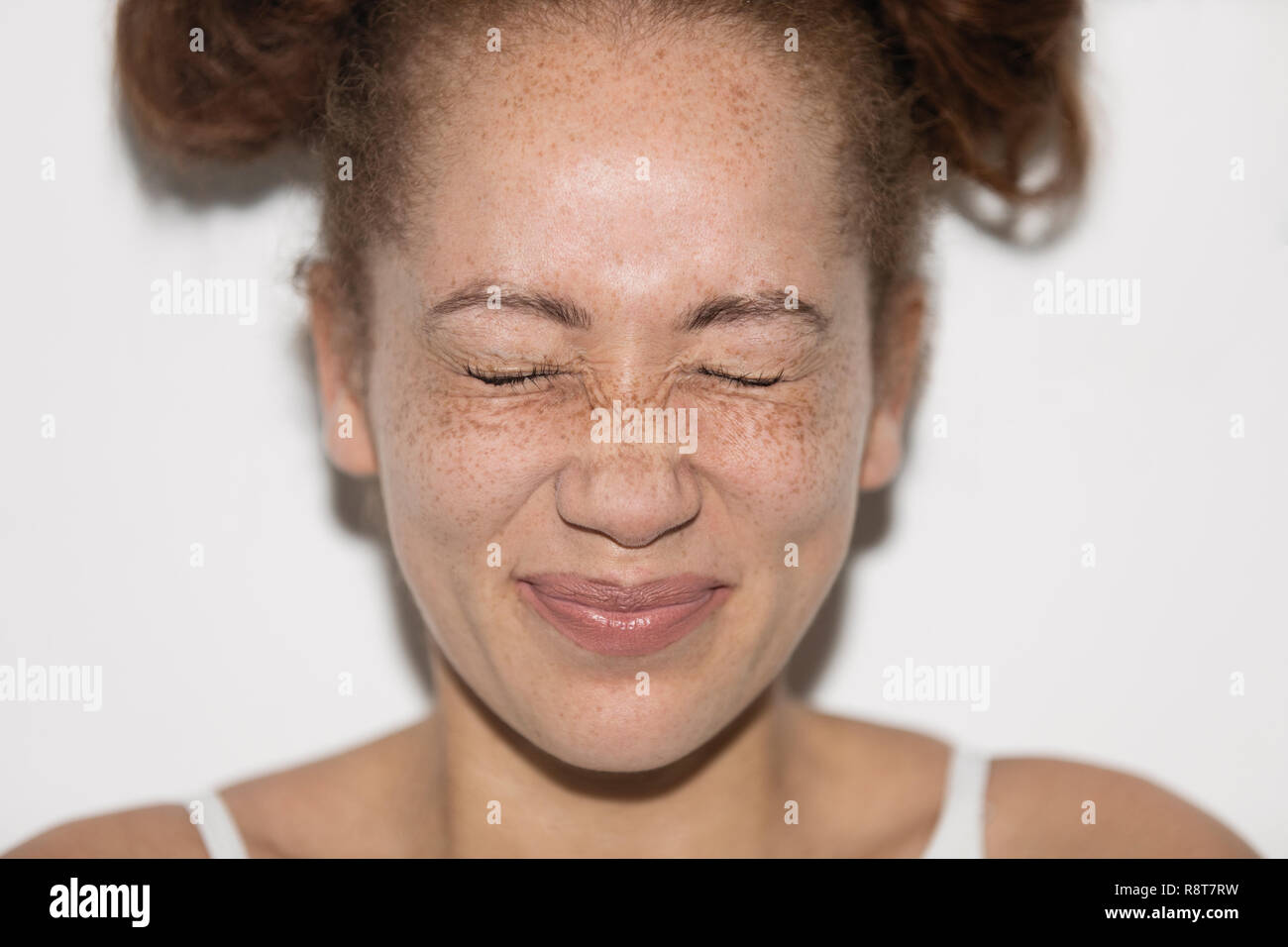 Portrait verspielte junge Frau mit Sommersprossen quetschen Augen Stockfoto