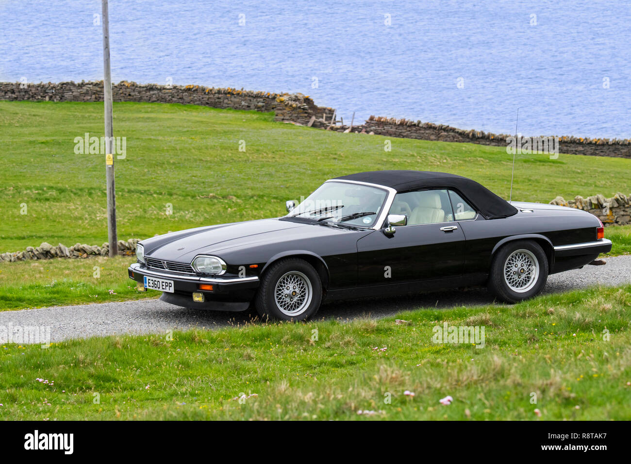 Schwarz 1988 Jaguar XJ-S V12 Cabrio Sportwagen entlang der Küstenstraße fahren Stockfoto