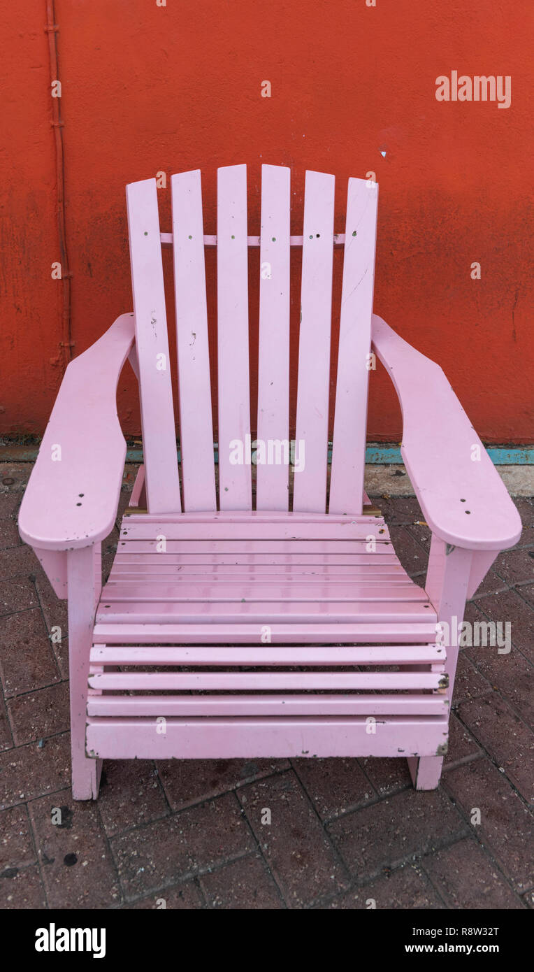 Rosa Holz Schaukelstuhl gegen orange Wand, Willemstad Curacao Stockfoto