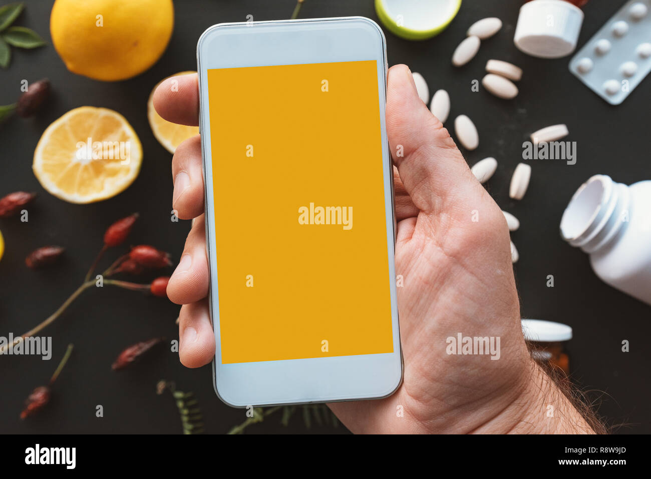 Smartphone mock up in männlicher Hand mit Kräutermedizin vs Pillen Konzept im Hintergrund Stockfoto