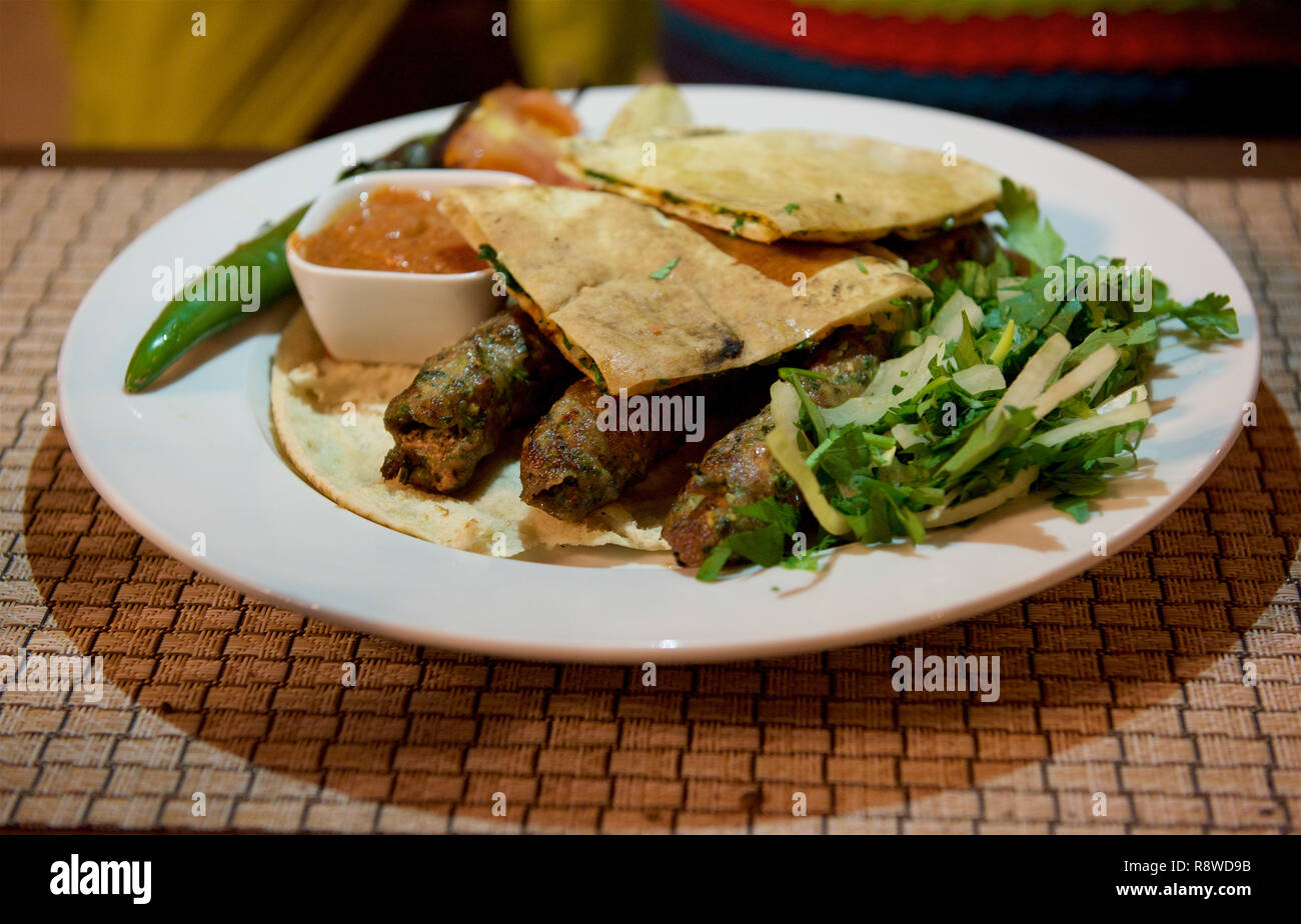 Kibbeh orientalisches Restaurant mit Rind, Lamm, Ziege oder das Kamel Fleisch serviert mit gebratenen grünen Salat, Pita, iolated. Reisen in den Nahen Osten land Königreich Jordanien Stockfoto
