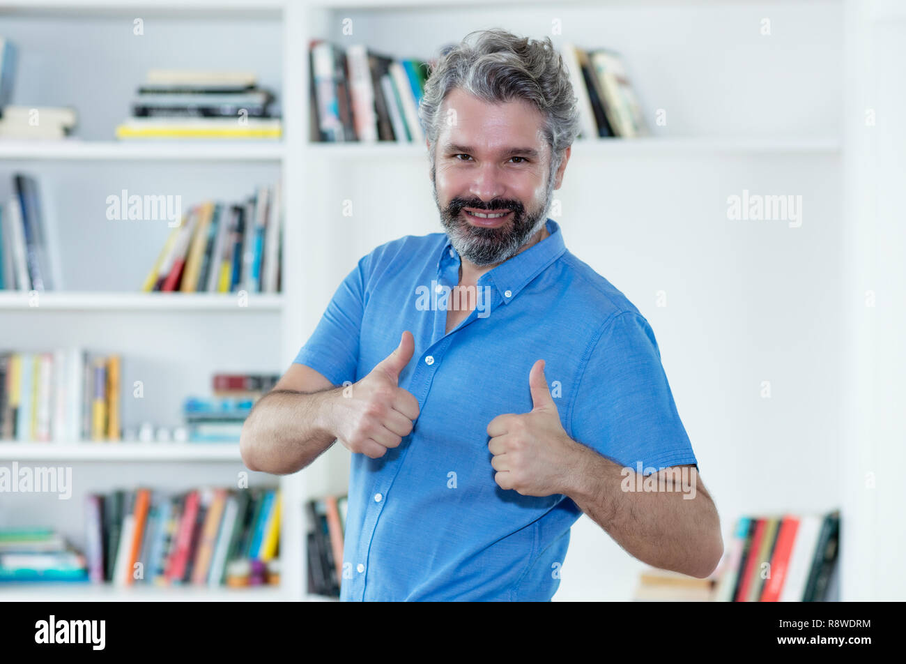 Glücklich im Mittleren alter Mann mit grauen Haaren zeigen beide Daumen nach oben Indoor zu Hause Stockfoto