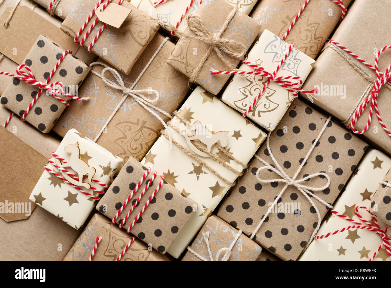 Weihnachten Hintergrund mit vielen dekorativen selbstgemachtes Geschenk Boxen in Braun Kraftpapier verpackt. Rot weiss Garn. Flach. Stockfoto