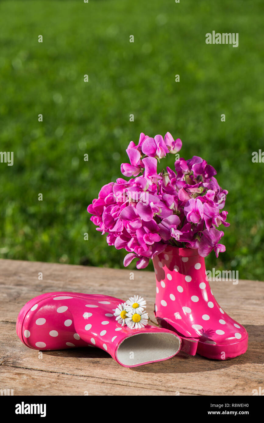 Rosa Gummistiefel auf hölzernen Hintergrund Stockfoto
