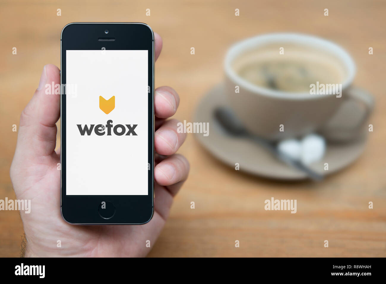 Ein Mann schaut auf seinem iPhone die zeigt die wefox Logo (nur redaktionelle Nutzung). Stockfoto