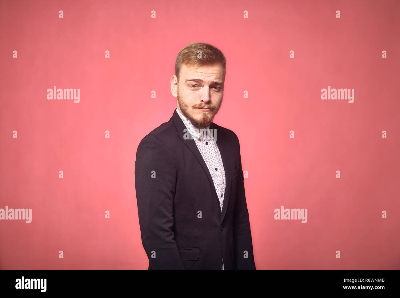 Ein junger Mann, 20-29 Jahre alt, lustig, Ausdruck, lustig mit den Augenbrauen, auf Kamera. rosa Hintergrund, studio Shot, Foto schießen. Stockfoto