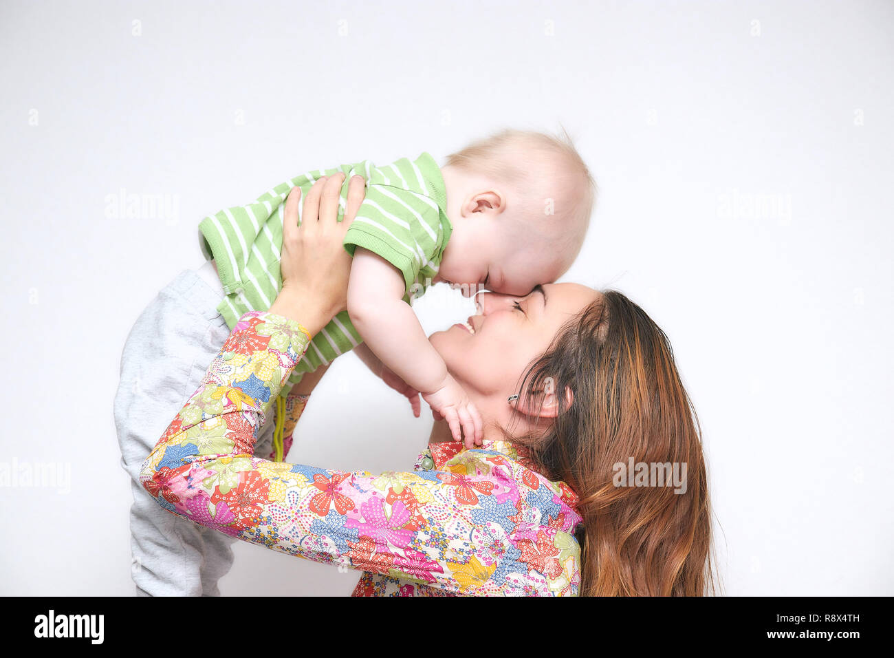 Brünette junge Mama, Mädchen, dass ein kleines Baby in ihren Armen tummeln. familiäre Atmosphäre mit einem Lächeln. happy family lächelt. Stockfoto