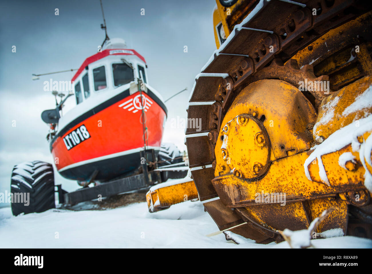 Traktor und Fischerboote im Schnee bei Aldeburgh Suffolk England Stockfoto