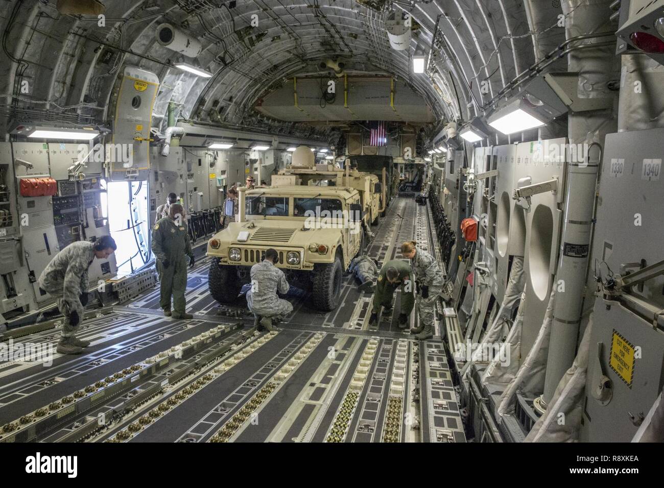 Us-Flieger mit 50. Antenne Anschluss Squadron, 452Nd Air Mobility Wing, Festzurren drei Marine Corps High Mobility Multipurpose Radfahrzeuge (Hmmwv), das in der Ladebucht des Air Force C-17 Globemaster III Flugzeuge sind während der strategischen Mobilität Übung (STRATMOBEX) auf März buchen Air Force Base, Calif., 12. März 2017 geparkt. STRATMOBEX ist eine Übung, die von der 1. Marine Logistics Group durchgeführt, um die Bereitschaft zu erhalten und zu schärfen, Fähigkeiten zur schnellen Bereitstellung von Personal und Ausrüstung in großem Maßstab erforderlich. Stockfoto