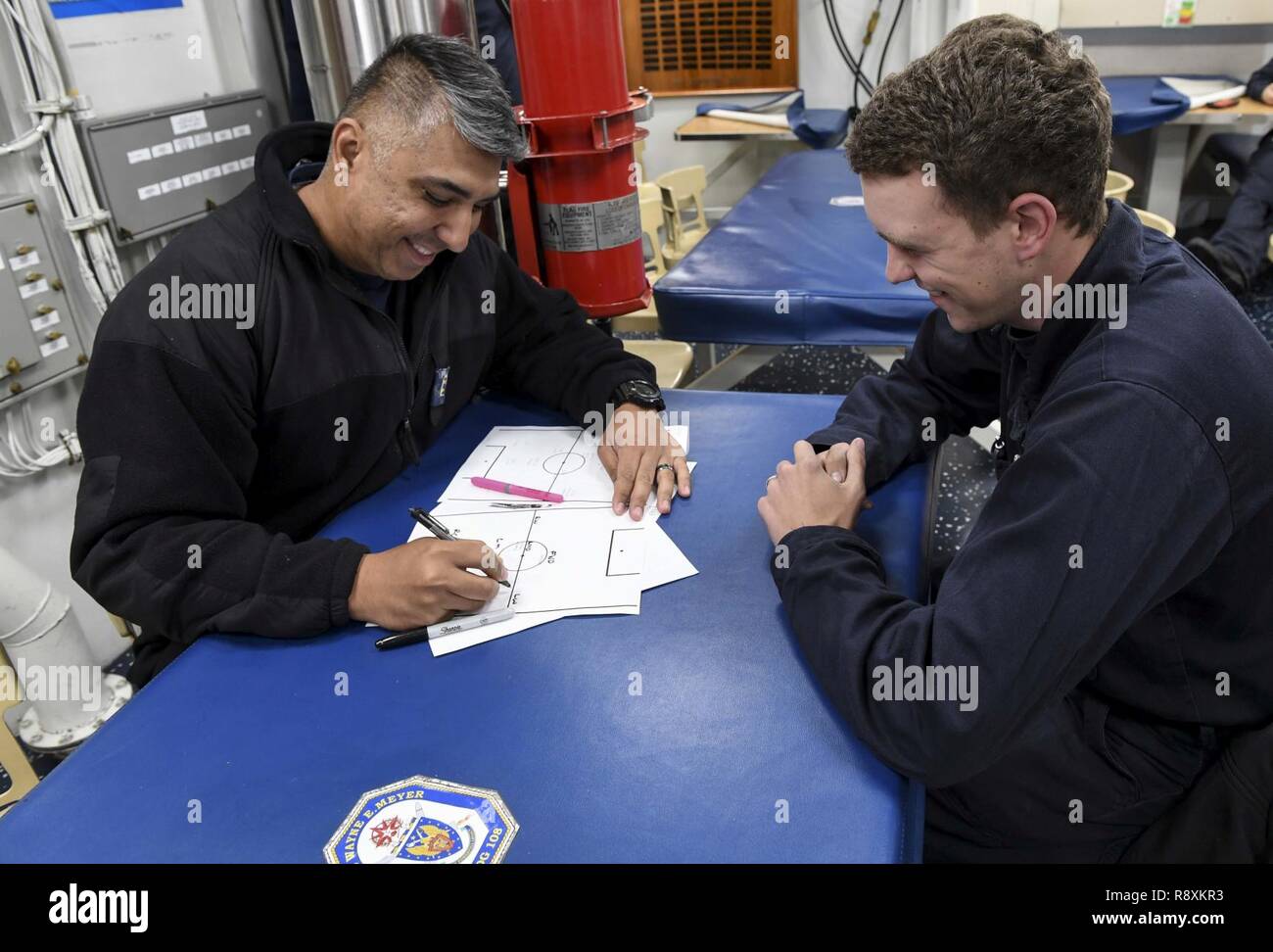 Gewässer ÖSTLICH DER KOREANISCHEN HALBINSEL (11. März 2017) Chief Warrant Officer Israel Villa (links), von Oceanside, Kalifornien, und Seaman Trevor Chastain, aus Seattle, Plan, Strategie für eine bevorstehende Fußball-Spiel an Bord der Arleigh-Burke-Klasse geführte Anti-raketen-Zerstörer USS Wayne E.Meyer (DDG108). Wayne E.Meyer ist in regelmäßigen Western Pacific Bereitstellung mit der Carl Vinson Carrier Strike Group als Teil der US-Pazifikflotte-Initiative US-Flotte 3. Befehls- und Steuerfunktionen in die Indo-Asia zu verlängern - Pazifik Region. Us Navy Flugzeugträger Streik Gruppen haben routinemäßig Stockfoto