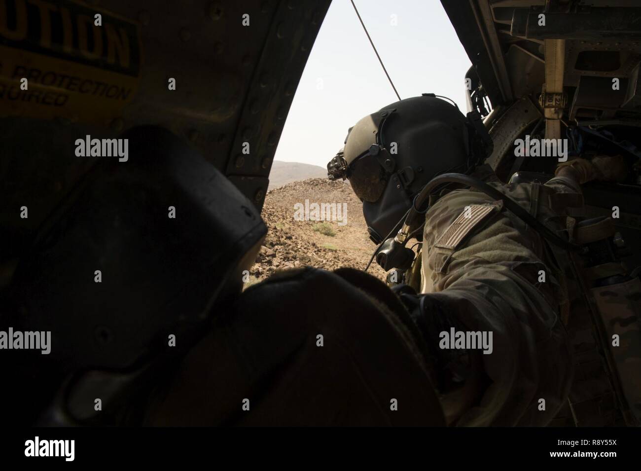 Ein HH-60 Pavehawk Antenne Gunner, von der 303Rd Expeditionary Rescue Squadron, prüft die Höhe des Flugzeuges bei einem März 2, 2017, um Lager Lemonnier, Djibouti. Die 303Rd EQRS sind Teil der 449th Air Expeditionary Gruppe Personal Task Force "Einziehung", wo Sie kontinuierliche Personal recovery Tätigkeiten ausüben, damit die regionalen Akteure gewalttätigen extremistischen Organisationen in Ostafrika und auf der Arabischen Halbinsel zu neutralisieren, um United States Interessen zu verteidigen und zu schützen. Stockfoto