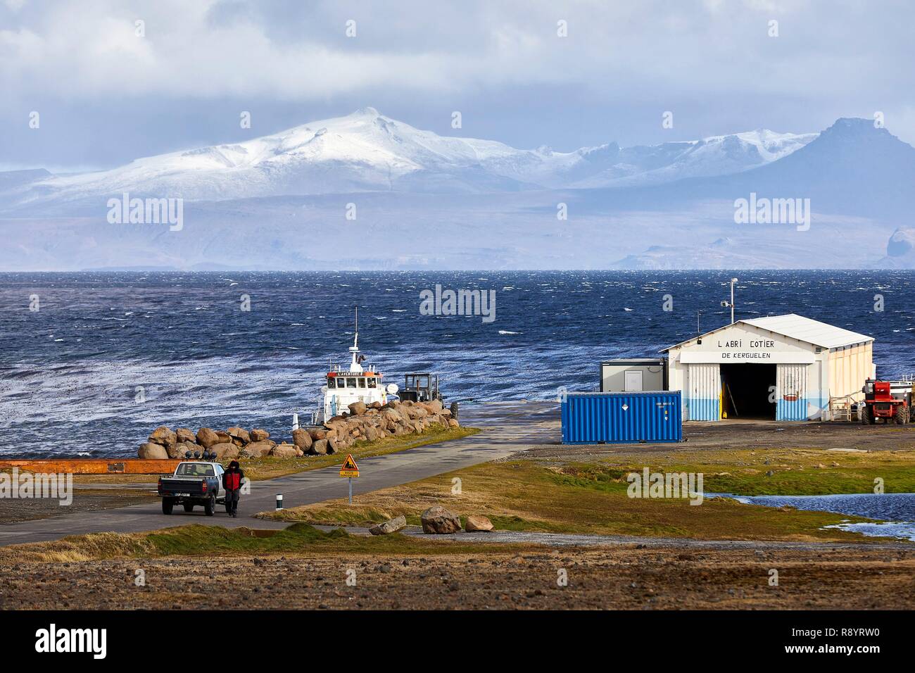 Frankreich, Französische Süd- und Antarktisgebiete (Taaf), Kerguelen, Port-aux-Français Gebäude mit Uhr die Ronac" Halbinsel im Hintergrund, das Abenteuer Barge II, das einzige Boot auf der Insel, im Frachtraum günstig ist, die flottille Gebäude (lokale Taucher, der mechanischen Werkstatt, Büro und Bosco workshop) war ironisch Die Küsten Tierheim genannt Stockfoto