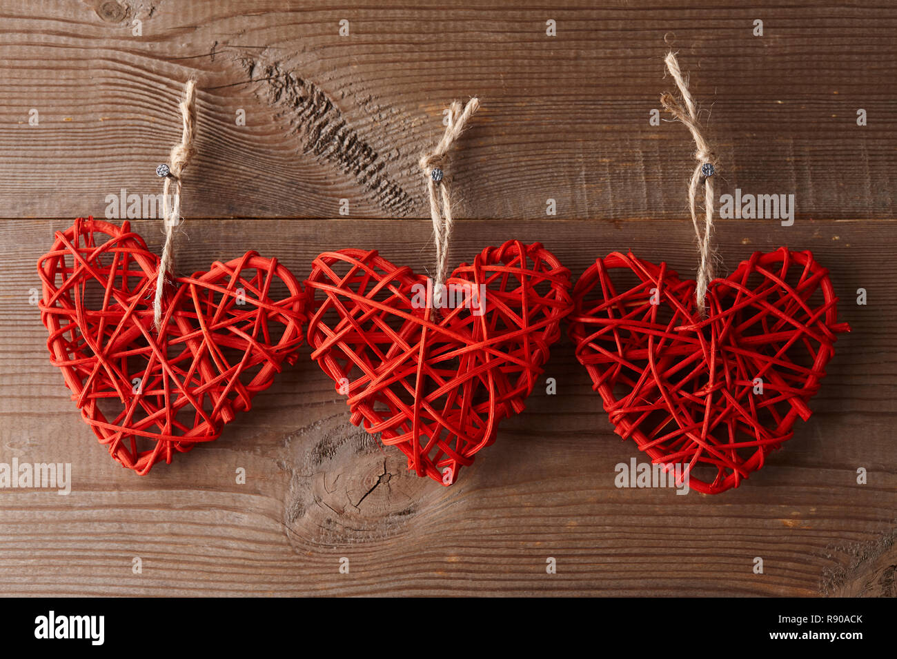 Red rattan Herzen hängen an alten Zaun am Valentinstag Stockfoto