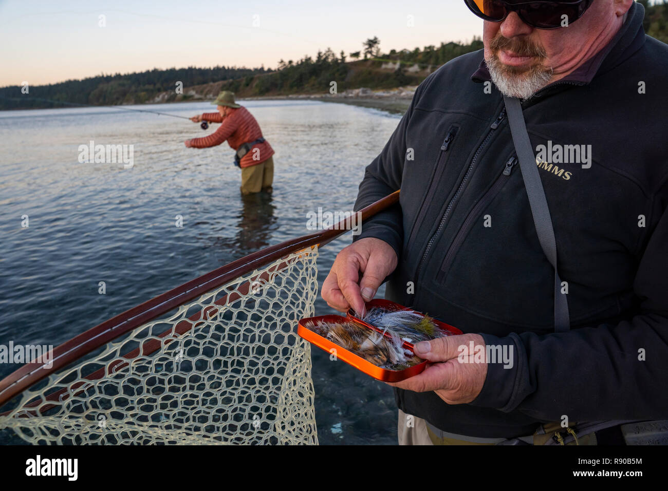 Eine Fly-fishing Guide prüft seine Fliege Sortiment für Lachs und searun Küsten cutthroat Forelle, während seine Kunden fliegen Fische im Hintergrund. Stockfoto