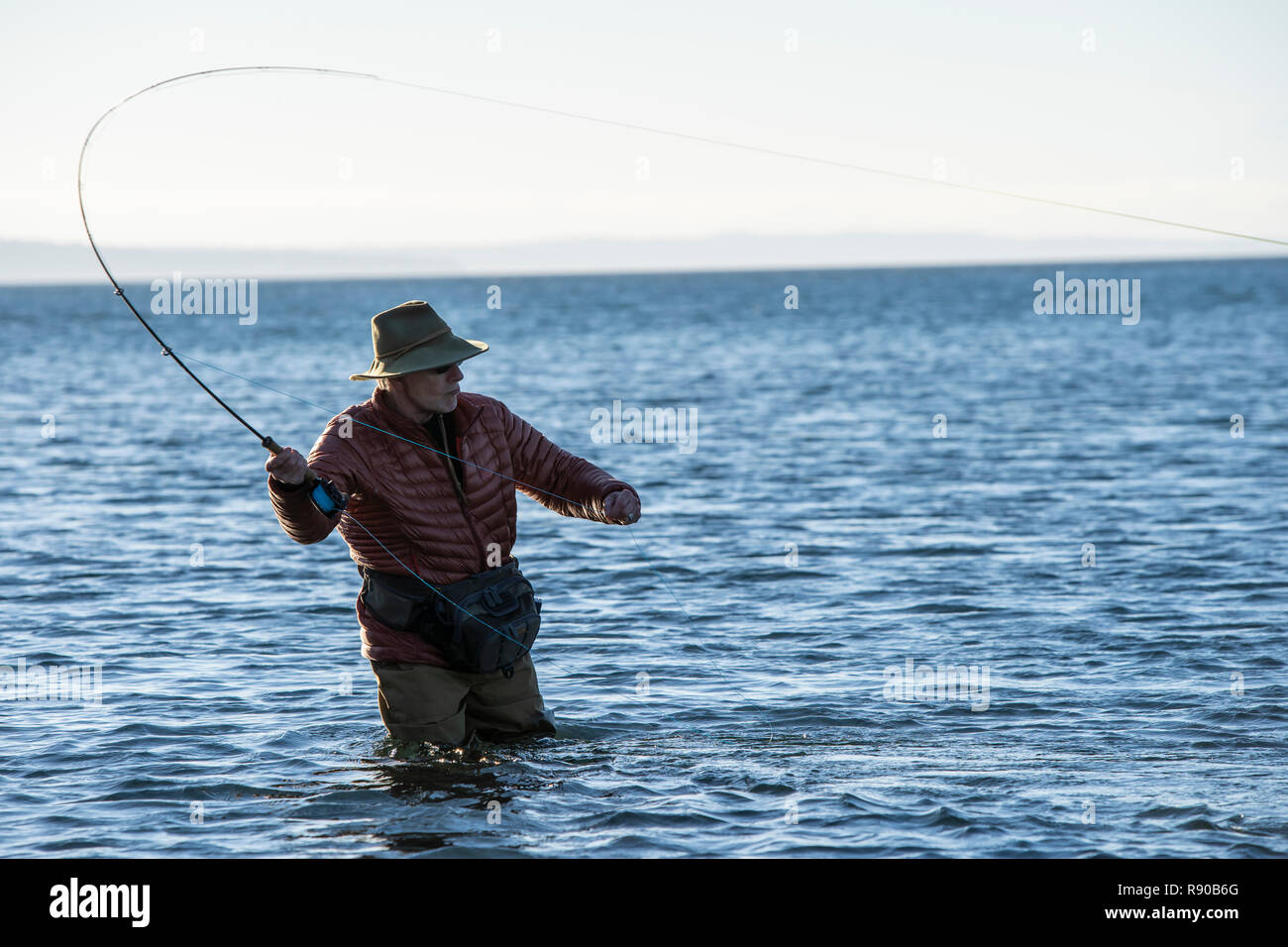 Ein Kaukasier Männlich Fliegenfischer wirft für searun Küsten Halsabschneider Forellen und Lachse in Salzwasser aus indischen Insel im Nordwesten von Washington State, USA. Stockfoto
