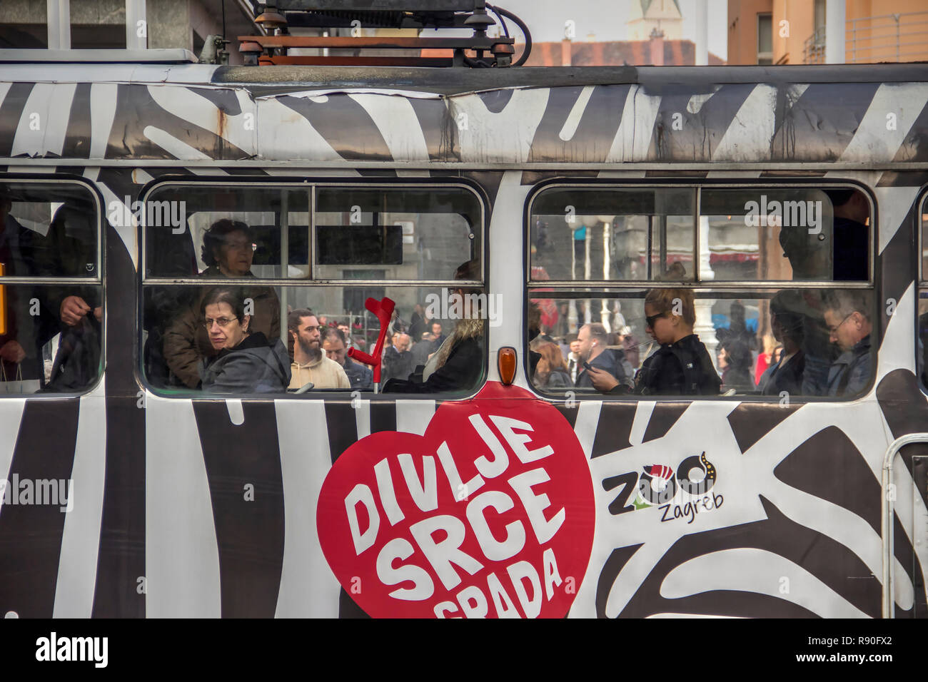 Zagreb, Kroatien, - Fahrgäste in der Straßenbahn mit einem Zebra Motiv mit einem Motto: 'Wilde Herzen' an der Ban Jelacic Platz Station lackiert Stockfoto