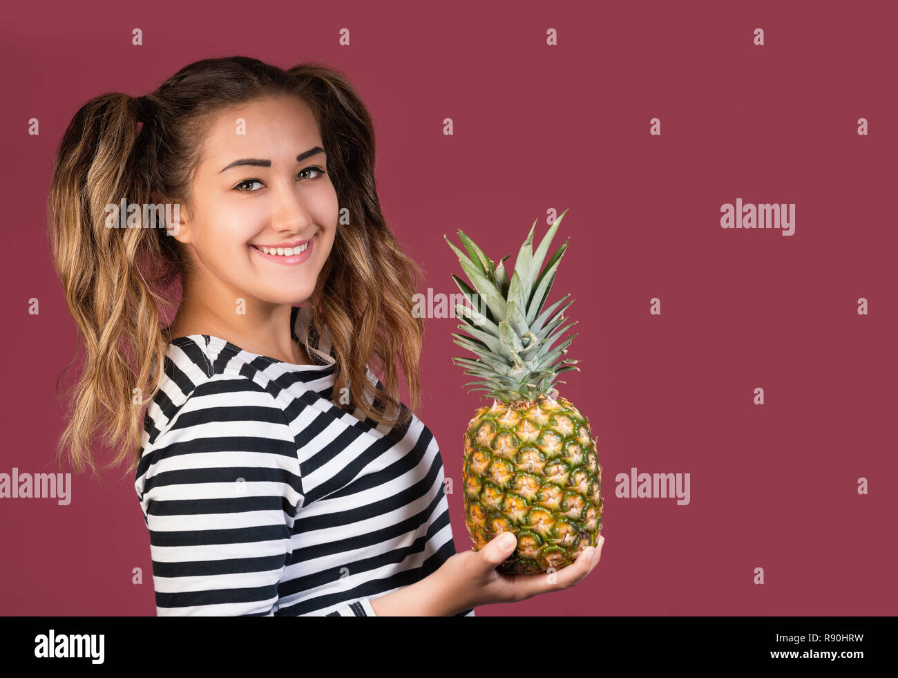 Portrait von cool Girl mit Ananas über bunte rosa Hintergrund. Gesunde Ernährung Konzept Stockfoto