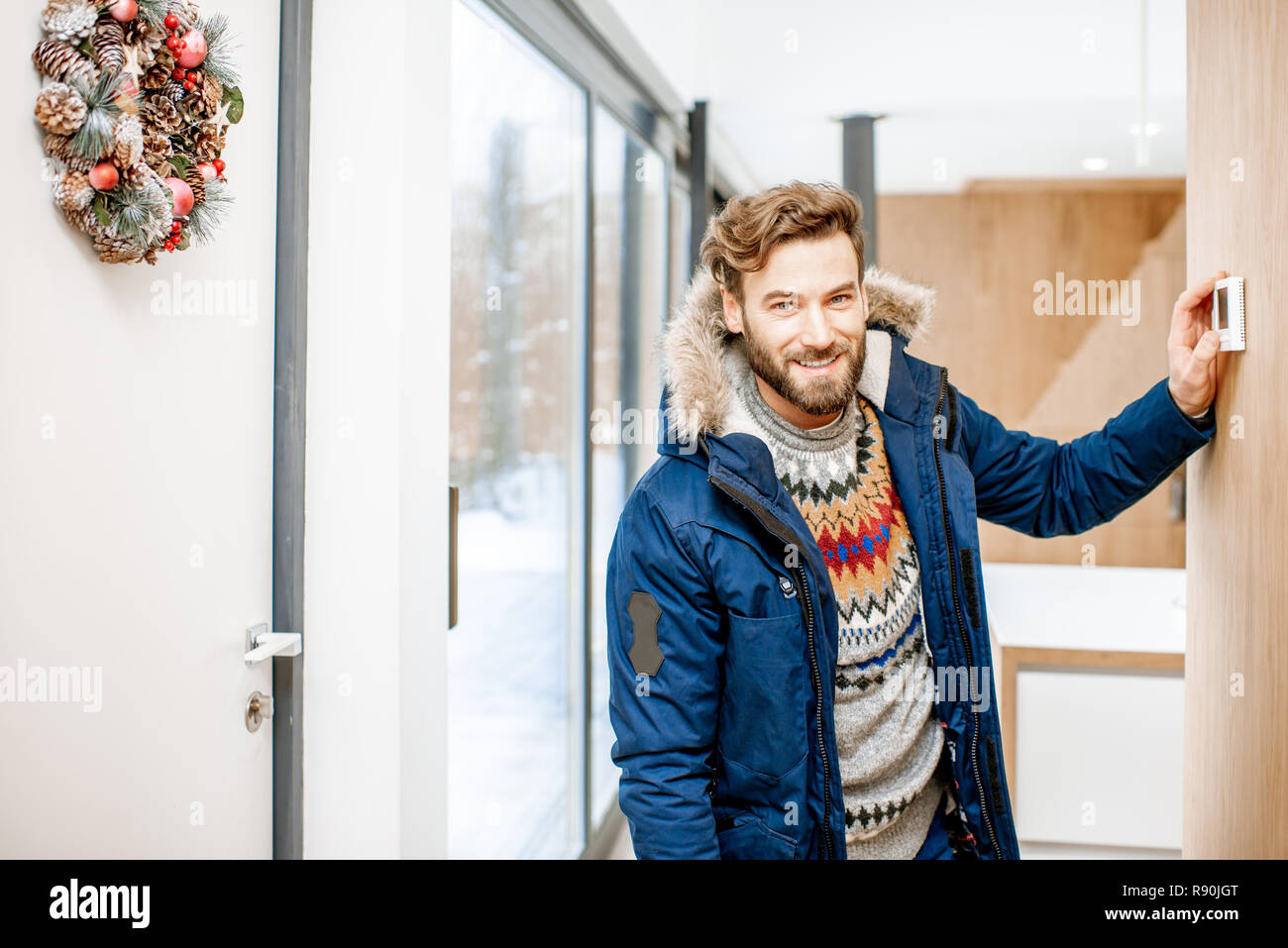 Mann in Winterkleidung Frieren einstellen Raumtemperatur mit elektronischer Thermostat zu Hause Stockfoto