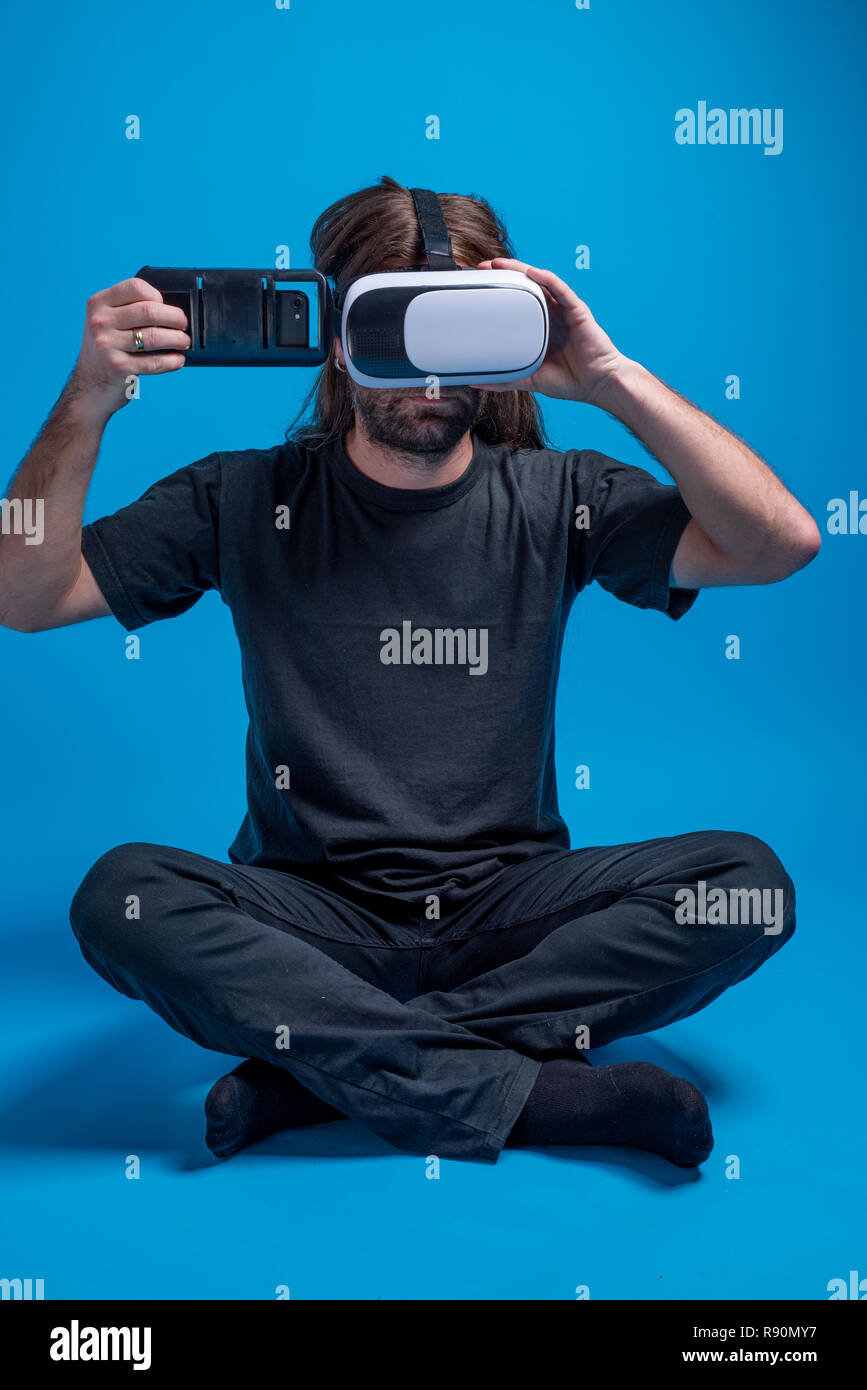 Männliche portrait tragen VR-Gang auf dem Boden Vorbereiten der Setup- und Einfügen Telefon Gerät. Virtuelle Realität Stockfoto