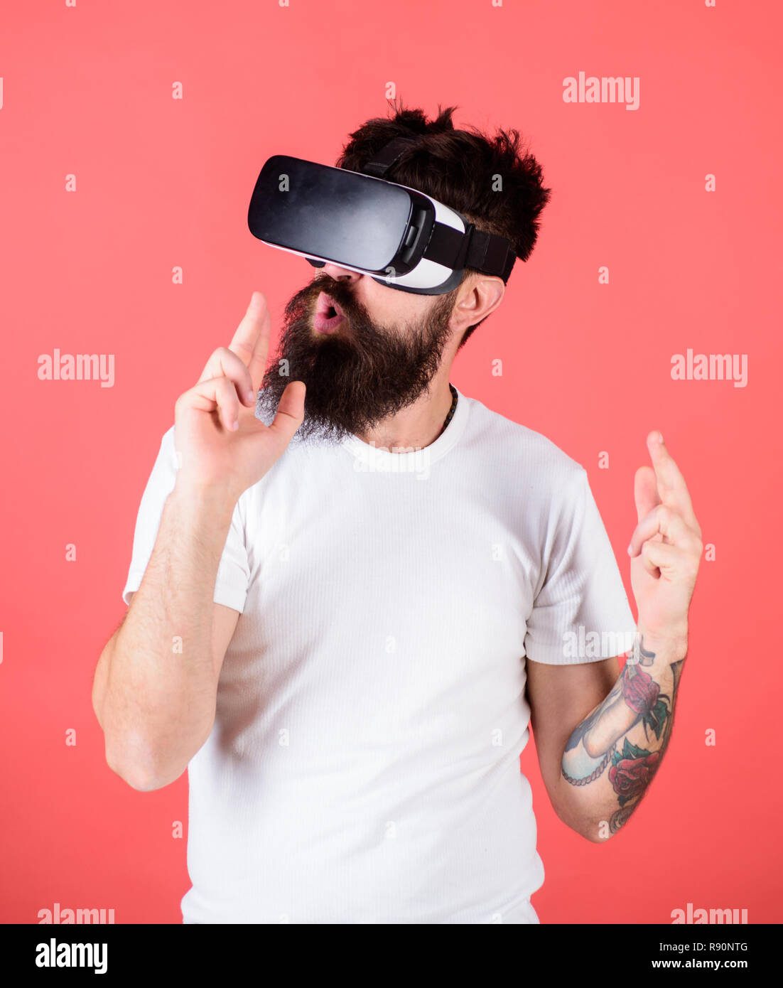 Man bärtige Hipster mit Virtual reality Headset auf roten Hintergrund.  Schießstand VR. First Person Shooter zeigt, wie süchtig VR werden könnte.  Hand Geste als Waffe spielen Shooter Spiel im VR-Brille Stockfotografie -