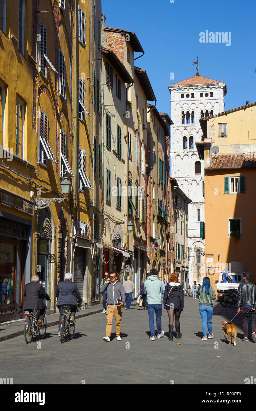 Lucca, Italien: Das Leben auf der Straße mit dem Campanile von San Michele im Hintergrund Stockfoto