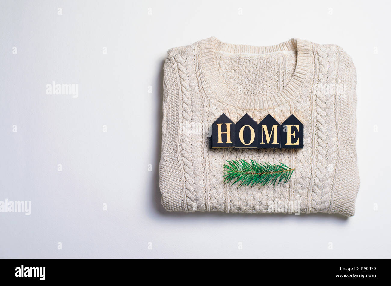 Gemütliche Home Winter Konzept, Home Buchstaben auf beiger Strickpullover und Tanne Zweig, Ansicht von oben Stockfoto