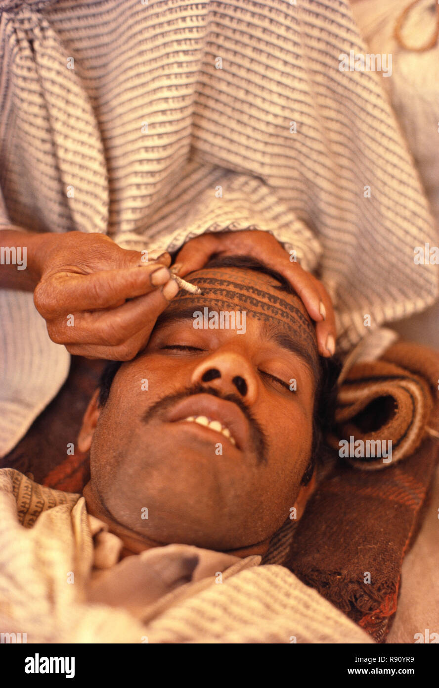 Ramnaami devotee beginnt mit der tätowierung die Stirn mit den sich wiederholenden Namen von Lord Ram von Experte Mitglied der Gemeinschaft, zentrale Indien. Stockfoto