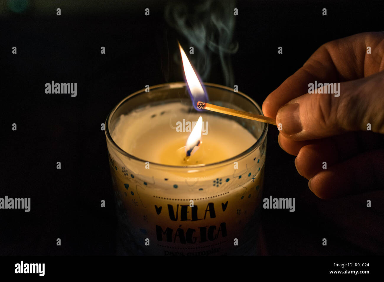 Ein Mann Hand ist eine Kerze mit einem Streichholz und sehen Sie zwei Flammen und der Rauch. Betet für uns, die Hoffnung ist notwendig. Ich mag riechenden aromatischen Kerze Stockfoto